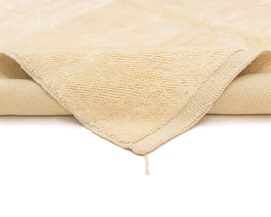 A plush, cream-colored towel with a textured surface mimicking the intricate patterns of a luxury rug.