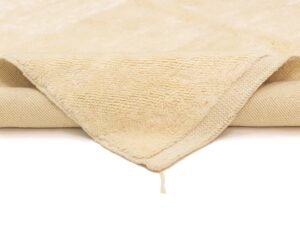 A plush, cream-colored towel with a textured surface mimicking the intricate patterns of a luxury rug.