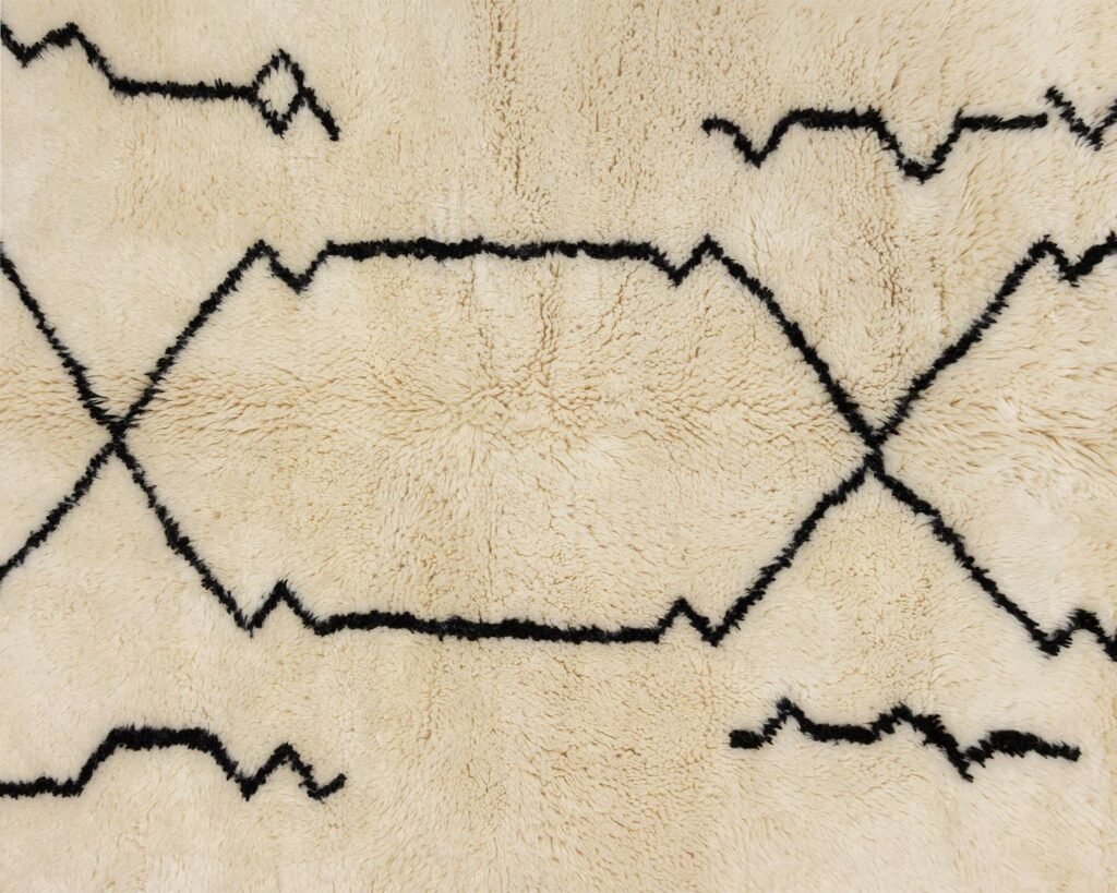 A plush beige rug adorned with a vibrant black geometric pattern of lines and zigzags.