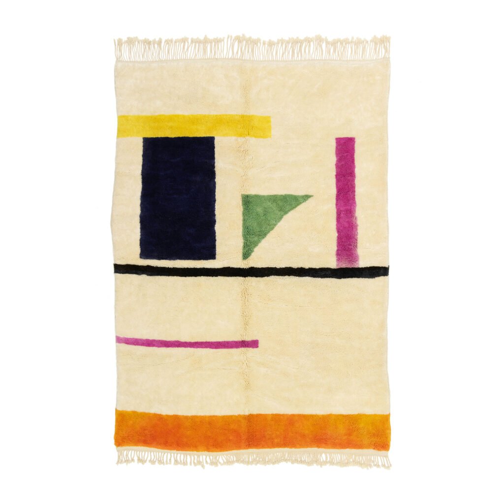 A beige rug with abstract geometric shapes in blue, yellow, green, pink, and orange, featuring fringe on the edges.