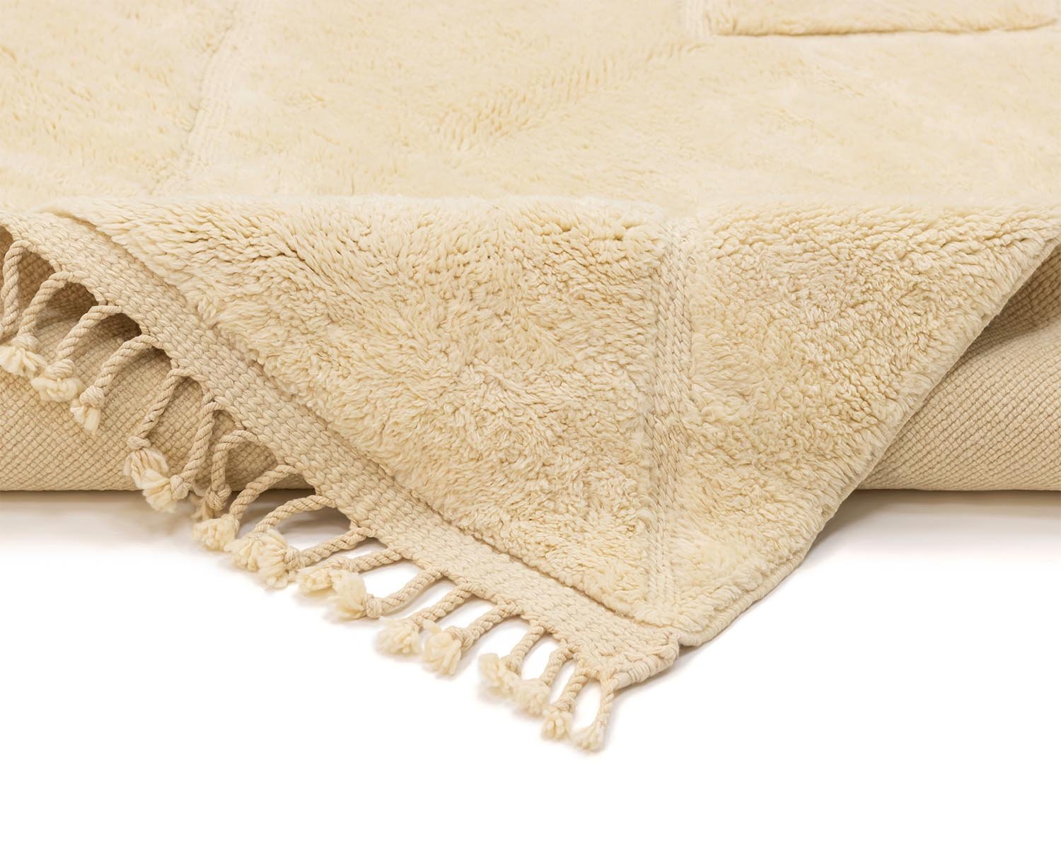 Close-up of a beige textured throw with fringed tassels along the edge, adding a touch of warmth and elegance to your decor.