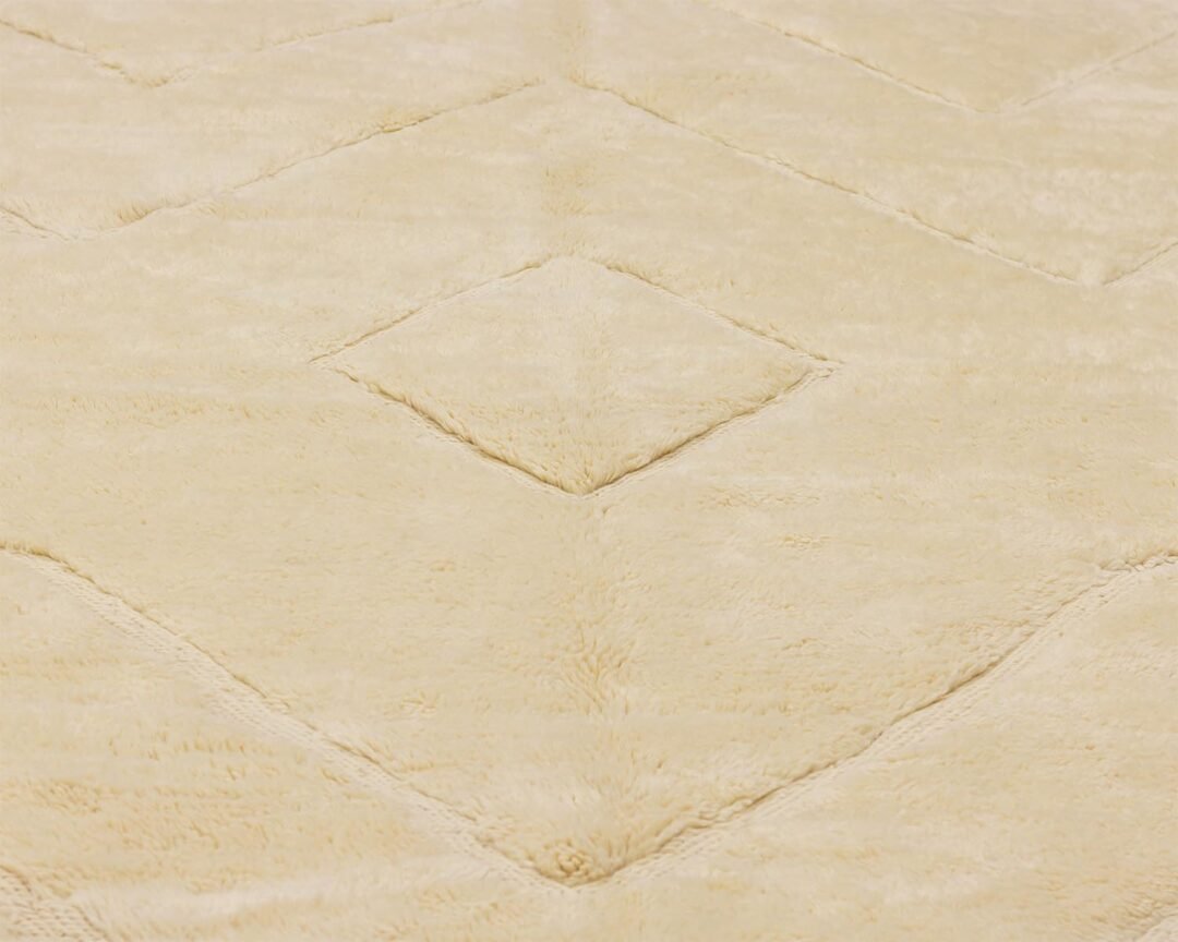 A close-up of a beige carpet showcases a geometric diamond pattern with a soft, textured surface, perfect for adding elegance to any room.