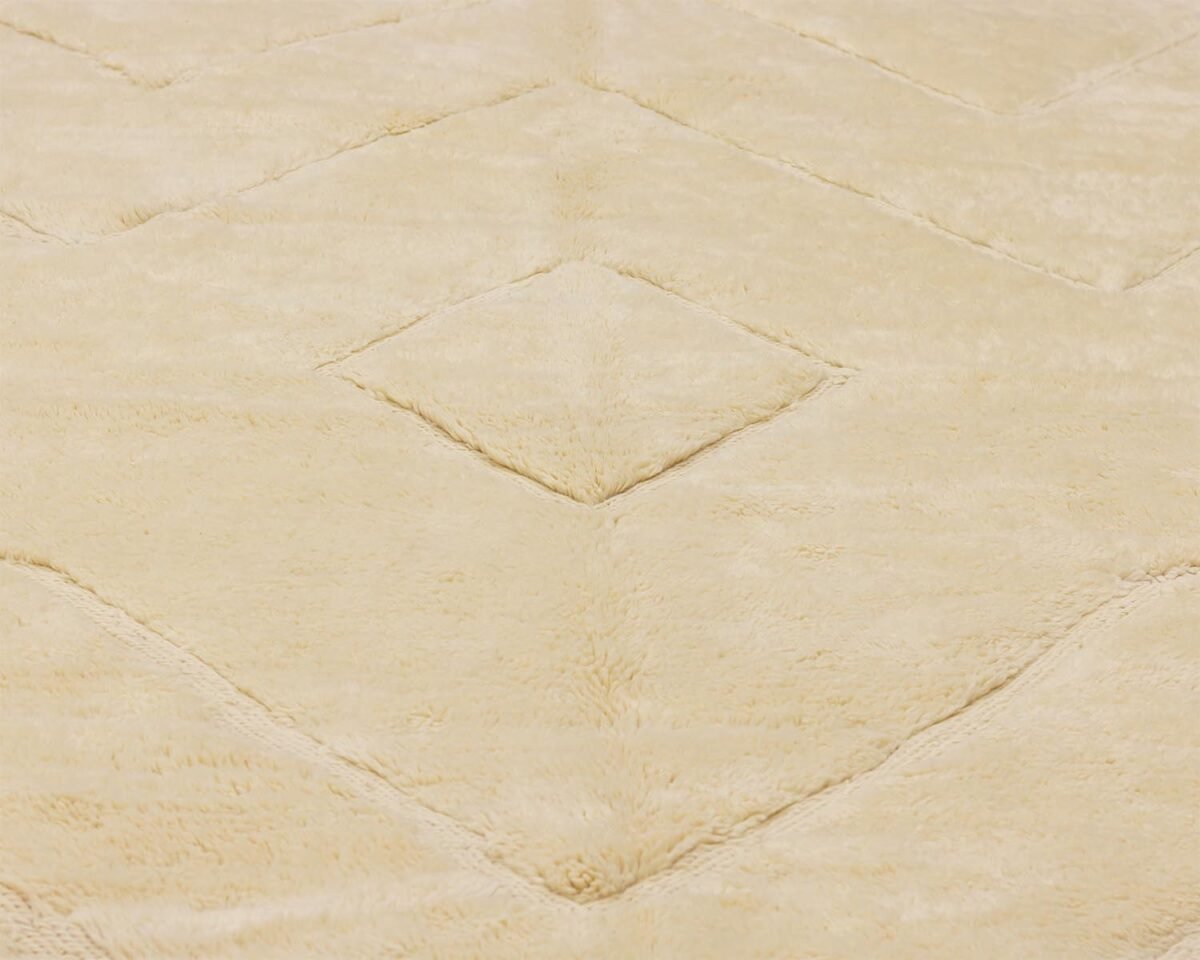A close-up of a beige carpet showcases a geometric diamond pattern with a soft, textured surface, perfect for adding elegance to any room.