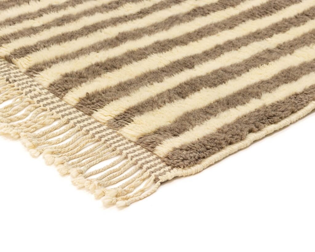 This brown and cream striped rug features fringe detailing on one edge, adding a touch of elegance to any room.