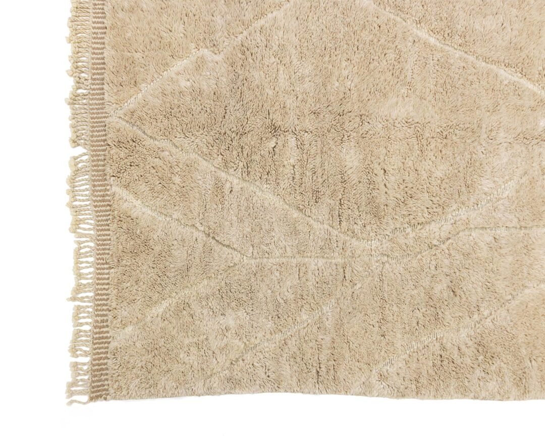 A luxury beige rectangular rug featuring a large leaf pattern, enhanced by fringed edges. This hand-knotted piece artfully combines elegance with design, making it a perfect addition to your home.