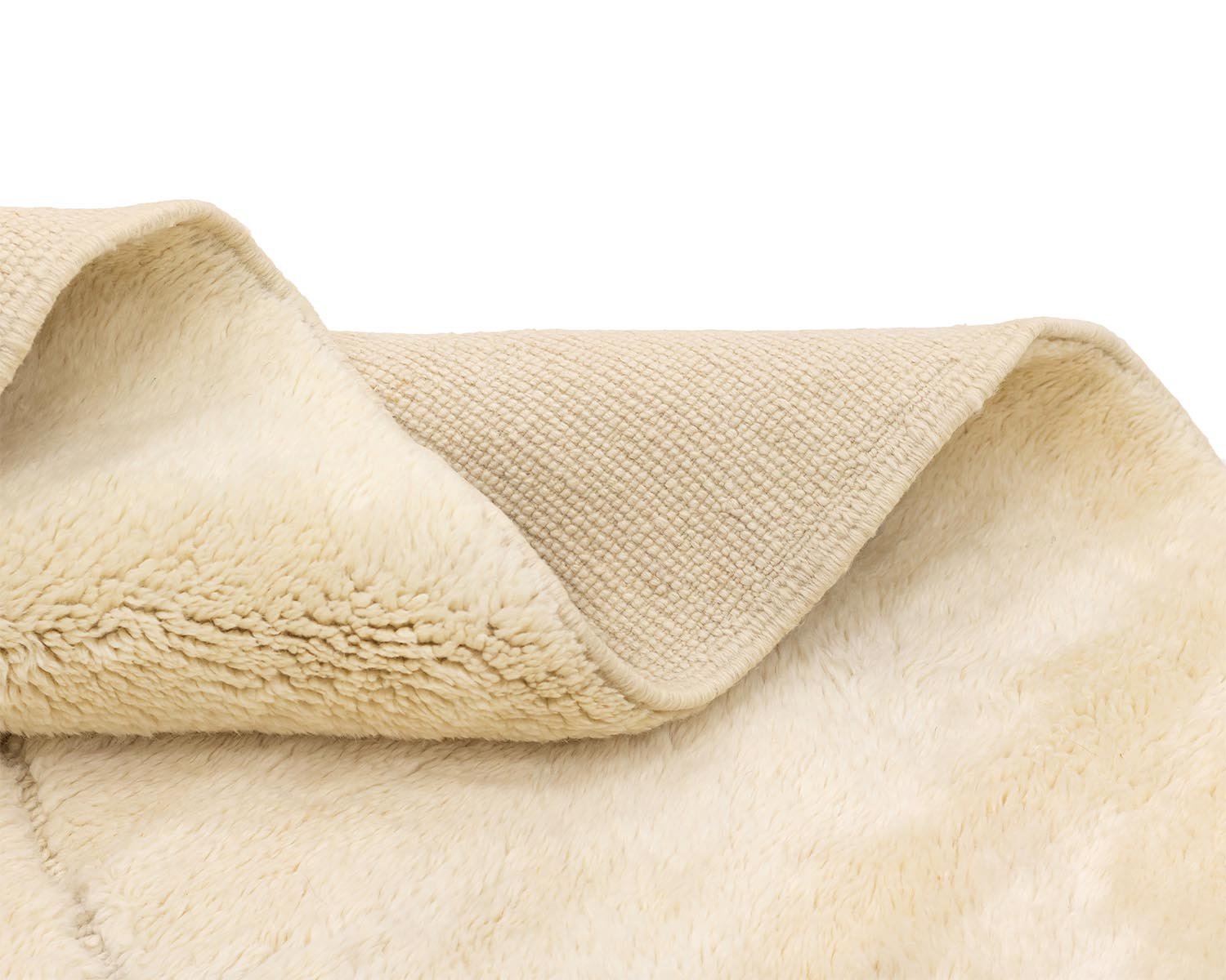 Close-up of a folded beige fabric revealing a fluffy, fleece-like side contrasted with a textured woven side.