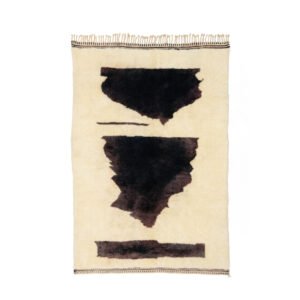A beige rug with abstract black shapes in the center highlights three distinct dark areas and includes a chic, fringed edge on one side.