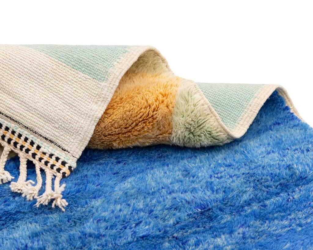 A folded blue and white woven blanket features a soft orange interior and fringe detailing on one edge, adding a touch of handmade home decor to any space.