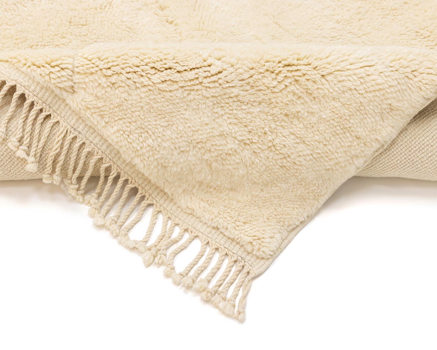 Close-up of a beige, fringed, fluffy throw partially folded, revealing its textured surface.