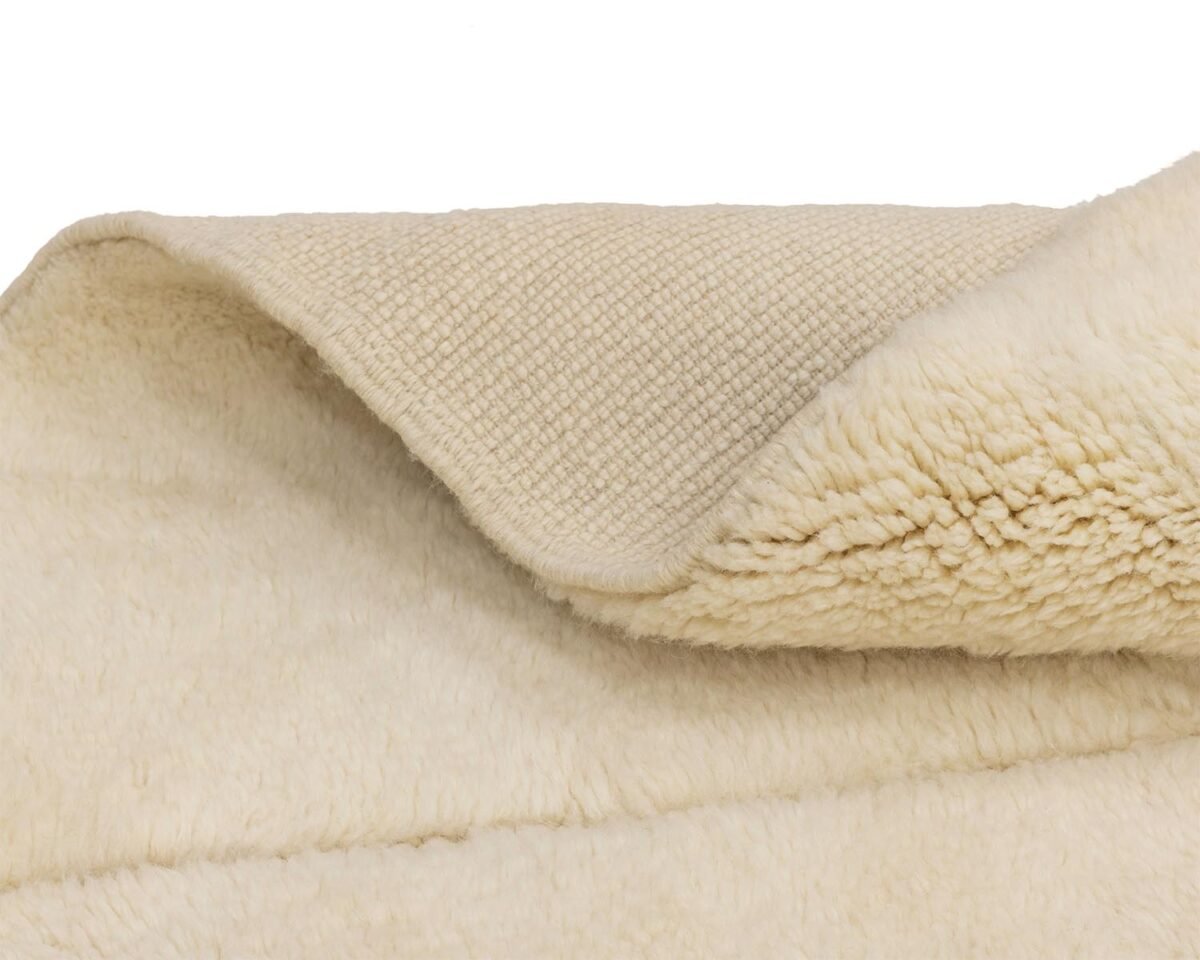 A close-up captures the soft, cream-colored fleece, highlighting its textured surface and a neatly folded corner.