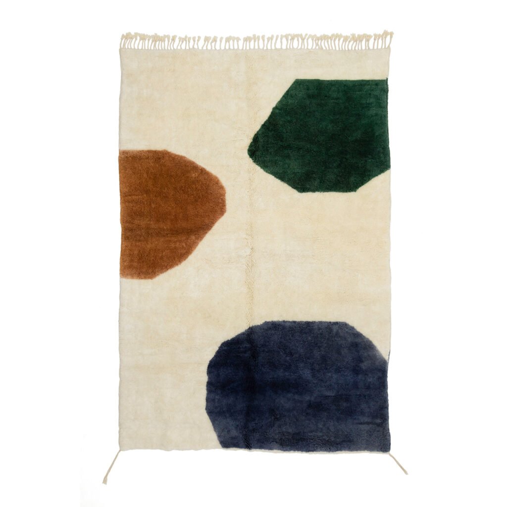 A rectangular rug with abstract shapes in brown, green, and blue on a beige background. Fringe detailing at the top edge.