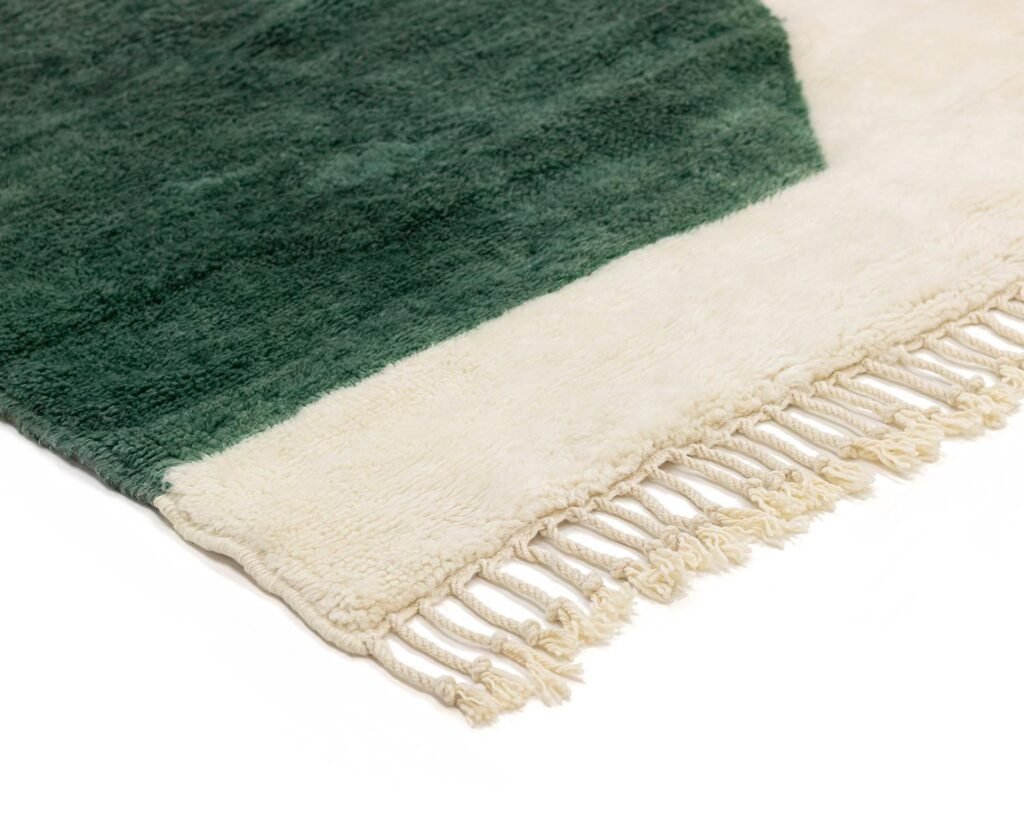 Close-up of a fringed fabric mat with dark green and cream sections.
