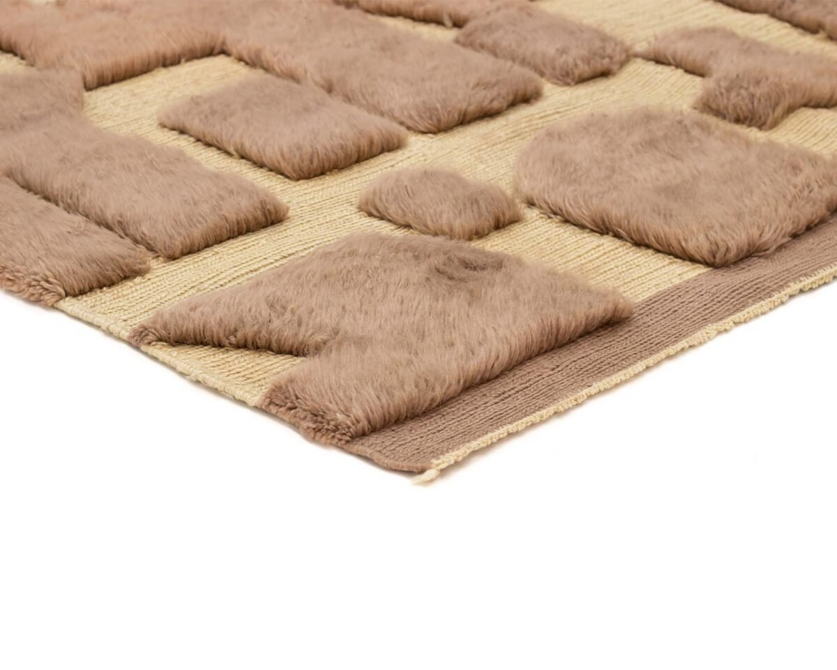 Close-up of an artisanal rug with a beige base and raised, soft, brown geometric patterns.