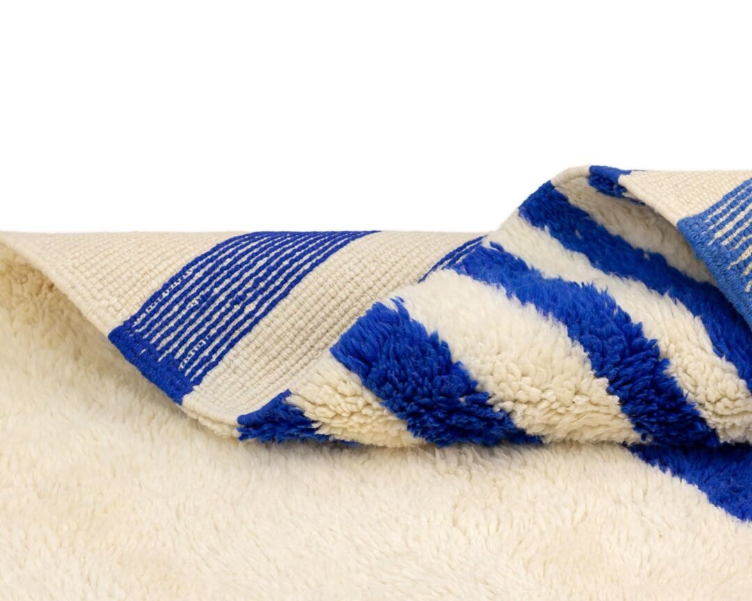 Close-up of a folded towel with blue and white stripes, beautifully capturing the contrast between its smooth and patterned surfaces.