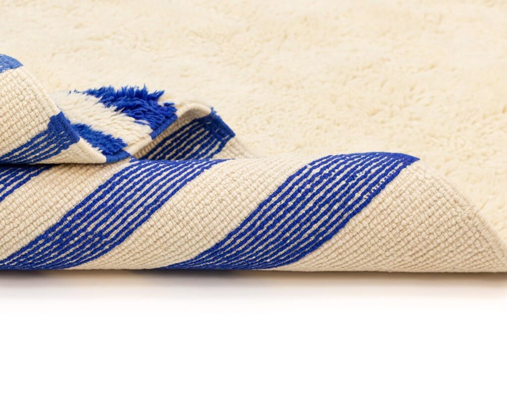Close-up of a folded rug featuring bold blue and white diagonal stripes on a crisp white background.