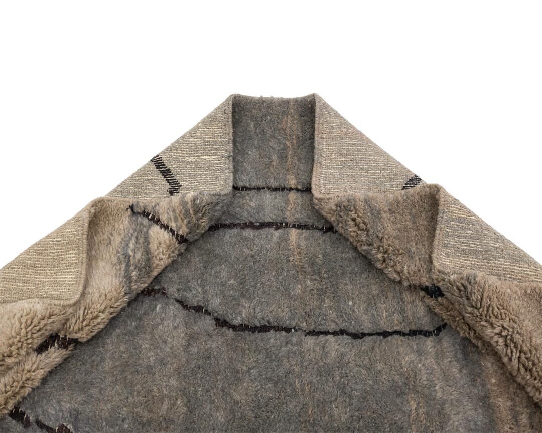 A close-up of a partially folded fleece reveals its soft, fuzzy interior and stitched edges, reminiscent of the cozy feel of hand-knotted textiles.