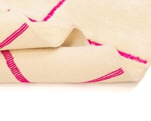 Close-up of a folded cream-colored textured fabric with bright pink woven stripes and a soft underside.