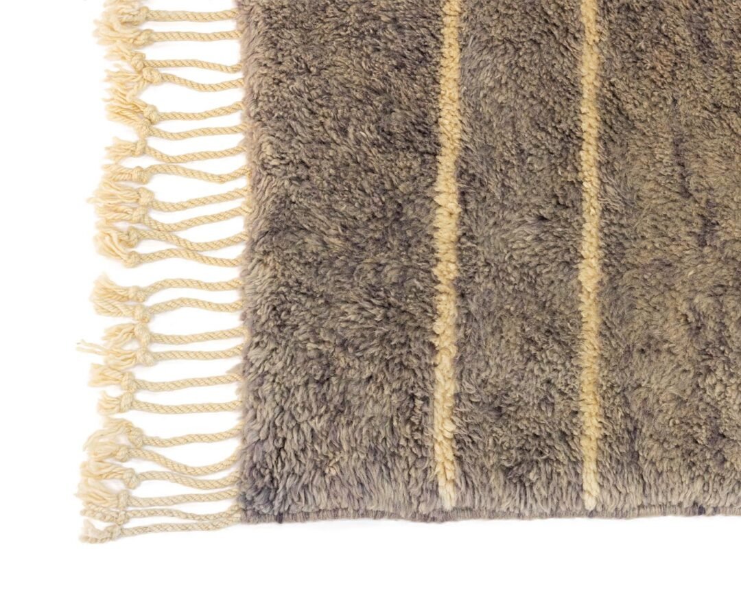 A close-up of a gray shaggy rug, showcasing its intricate texture and soft beige fringes gracefully lining the left edge.