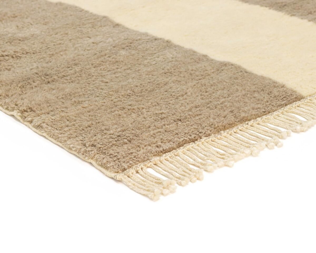 A close-up of a cozy, beige and brown striped rug showcases its fringed edges on one side.