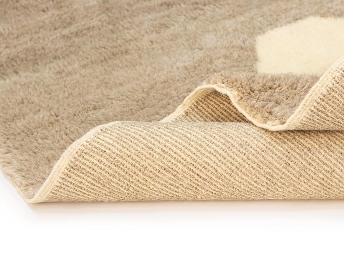 Close-up of a beige rug corner gently folded over, showcasing its intricately woven underside.