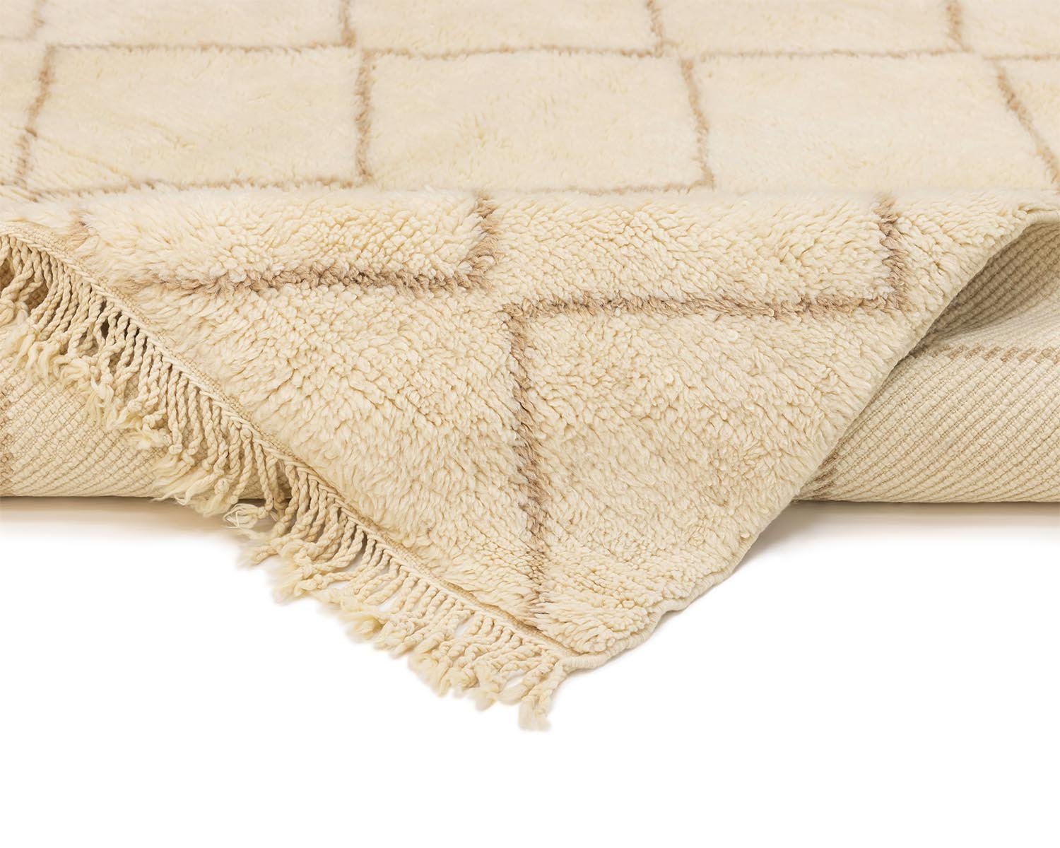 A luxurious, beige wool-textured rug with a checkerboard pattern is displayed. Partially folded, it reveals fringed edges and exudes the beauty of a Moroccan hand-knotted design.