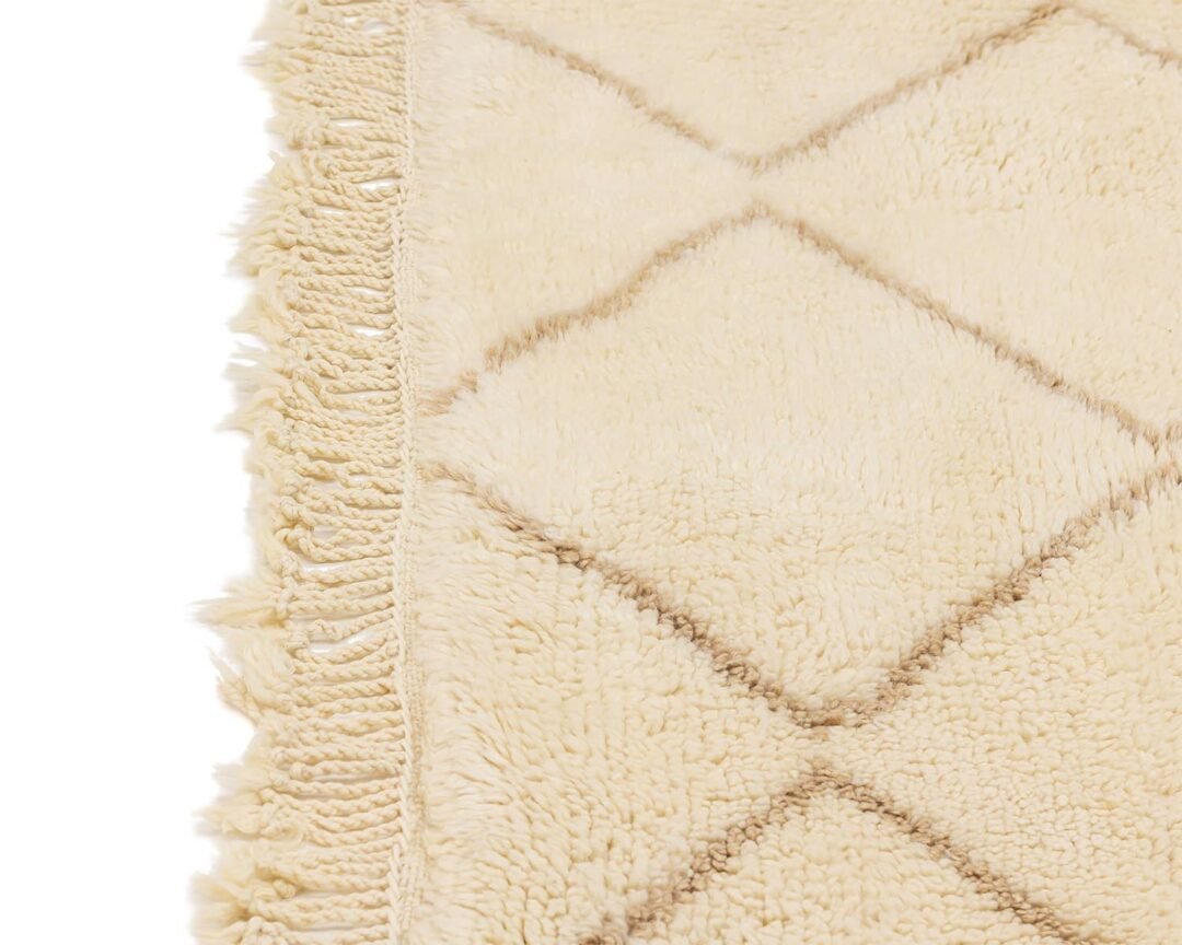 Close-up of a beige shaggy rug featuring a stylish diamond pattern and fringed edge.