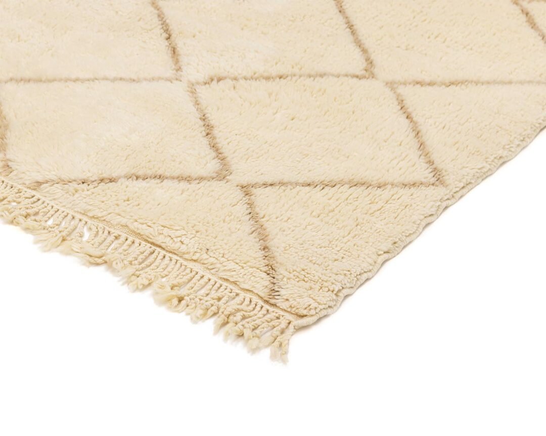 A beige, fluffy rug features a stylish diamond pattern and charming fringed edges, adding warmth to any room.