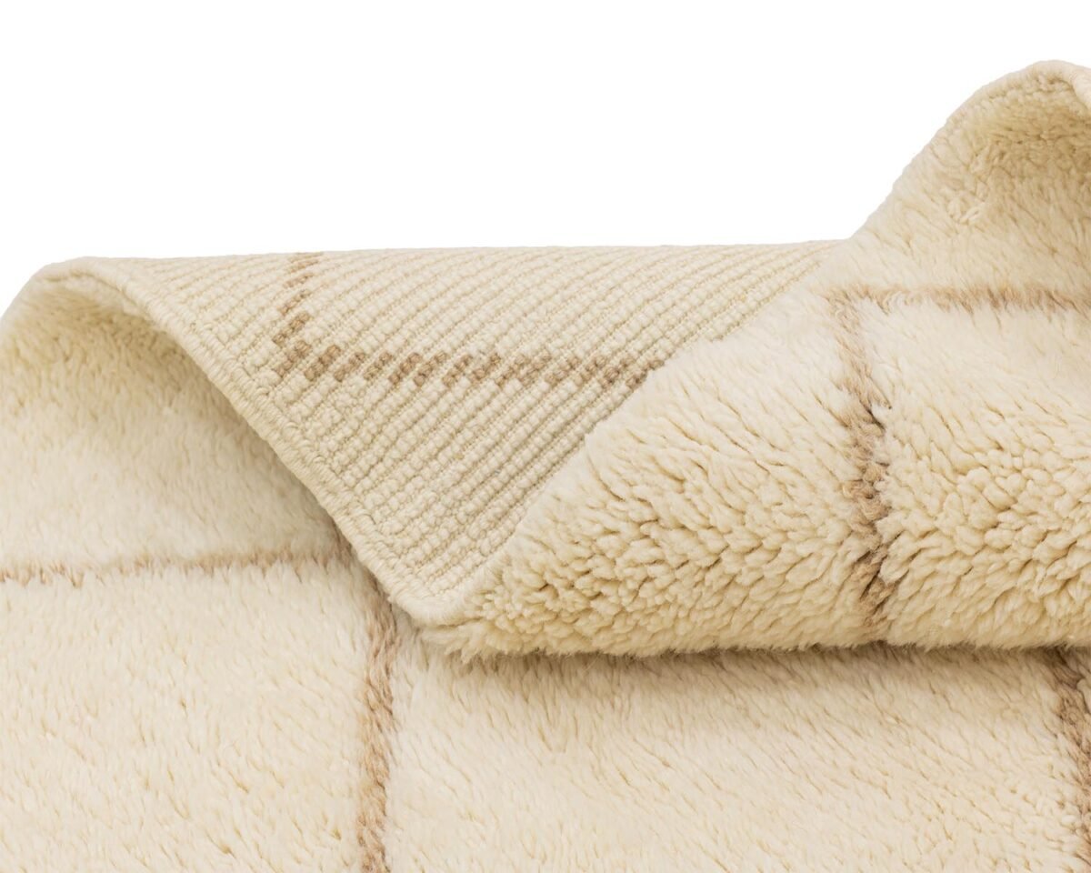 Close-up of a folded beige plaid textile with a soft, fuzzy texture and checkered pattern, perfect for cozying up on a chilly evening.