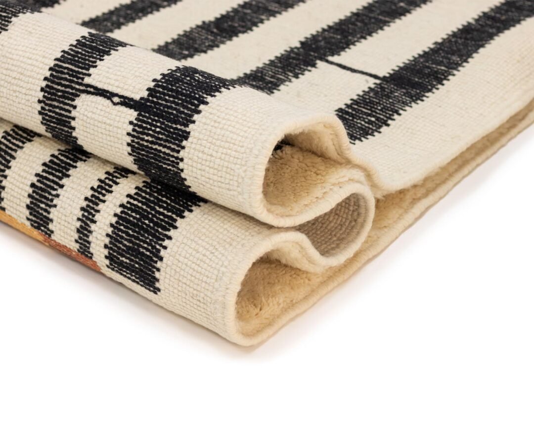 Folded black and white striped woven rug, beautifully showcasing its intricate texture and sophisticated pattern.