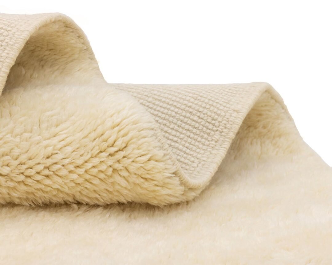 Close-up of a cream-colored fleece folded over itself, showcasing both its fluffy and plush surfaces.