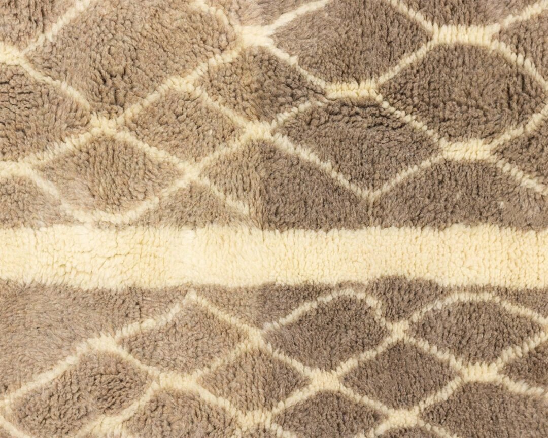 This luxurious Moroccan rug features a close-up of its brown and cream geometric pattern, showcasing intricate diamond shapes. Its plush texture adds an elegant touch to any space, making it a desirable choice for those seeking both comfort and style.