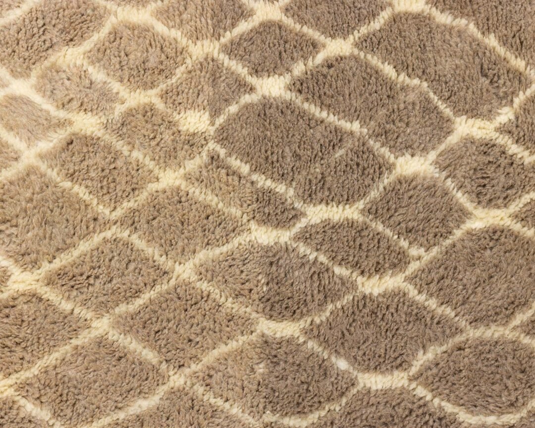 Close-up of a light brown, textured fabric with a diamond pattern, reminiscent of a luxurious Moroccan rug.