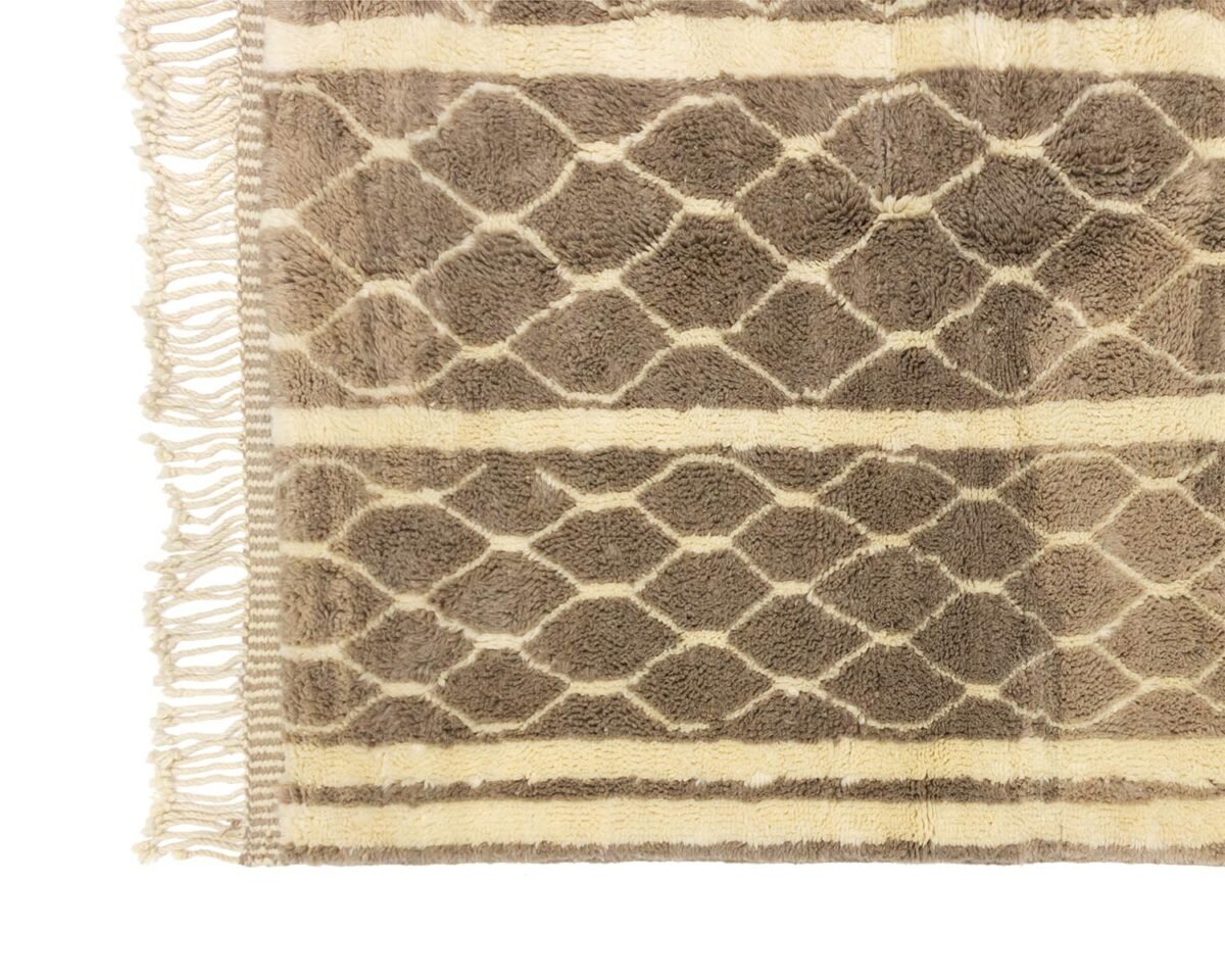 A luxurious hand-knotted Moroccan rug featuring a section with brown and beige hexagonal patterns and fringed edges.