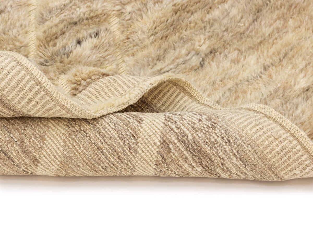 Close-up of a corner of a beige textured rug with the underside folded over, revealing a contrasting woven design.