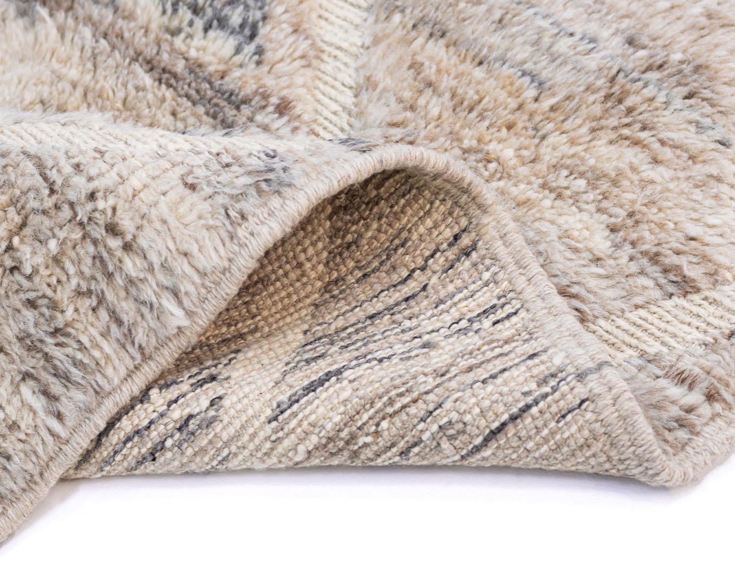 Close-up of a beige and gray Moroccan rug with a raised, textured pattern and a softly curved edge.