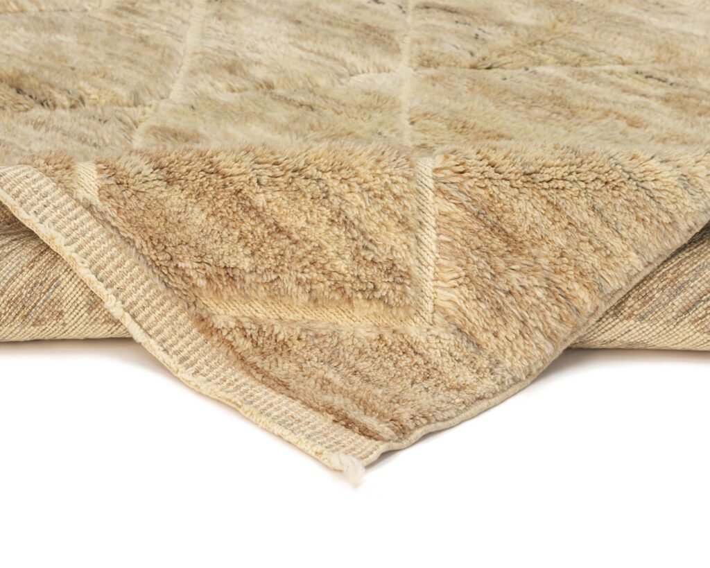 A close-up of a folded, soft, beige fur-like throw reveals its plush texture and layered design.
