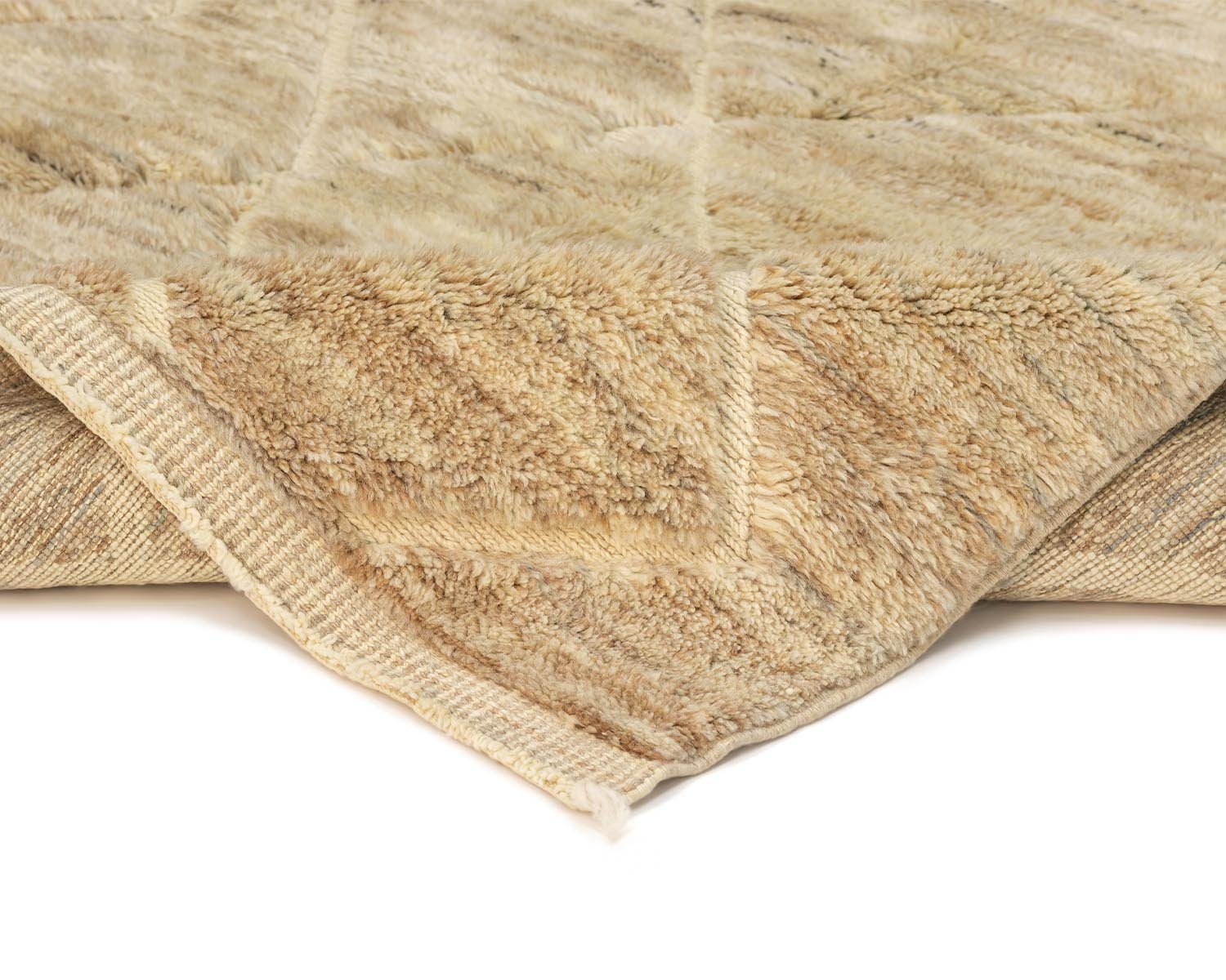 A close-up of a folded, soft, beige fur-like throw reveals its plush texture and layered design.