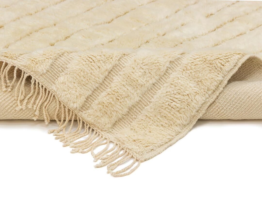 A beige textured rug with fringe tassels on the edges is artfully draped, adding an elegant touch to any room.