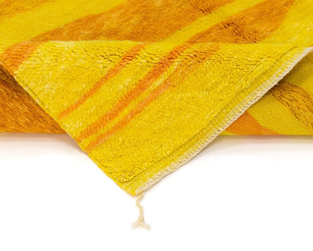 A close-up of a yellow-orange striped towel with a folded corner showing its texture and a hanging loop.