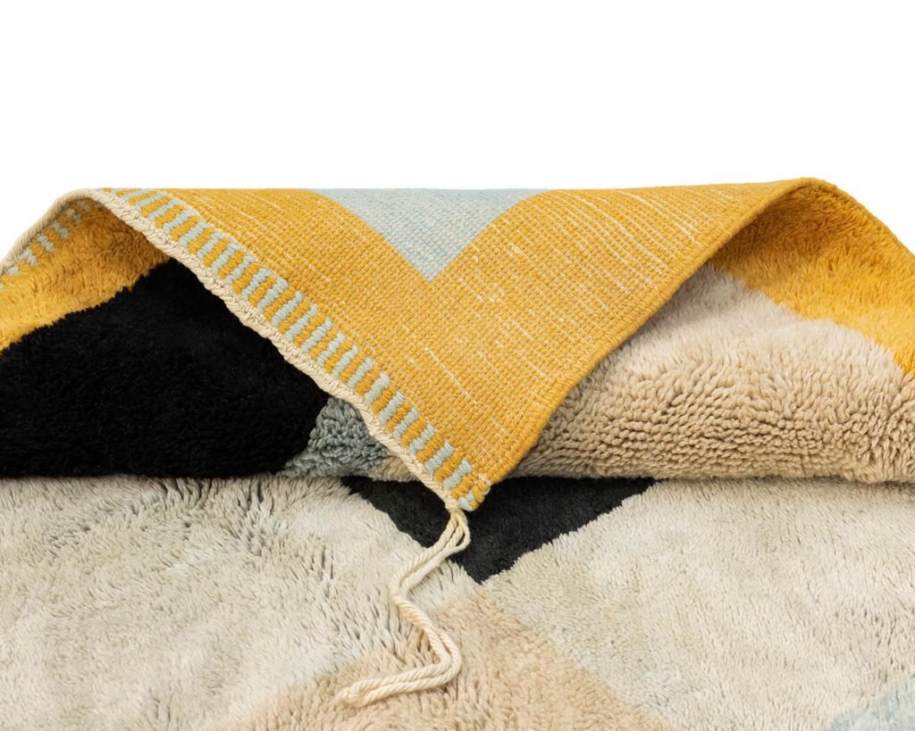 Yellow and cream geometric pattern textile with a folded corner revealing a textured underside.