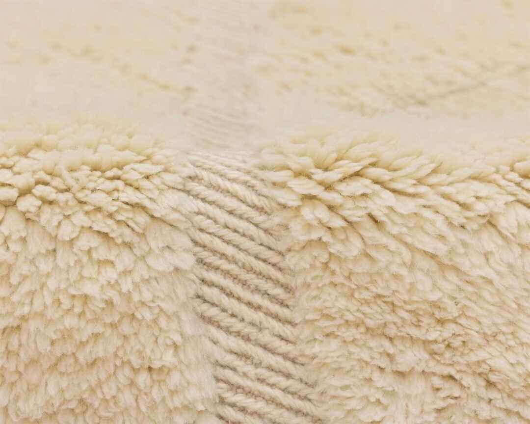 Close-up of a fluffy beige material featuring a woven zigzag pattern in the center.