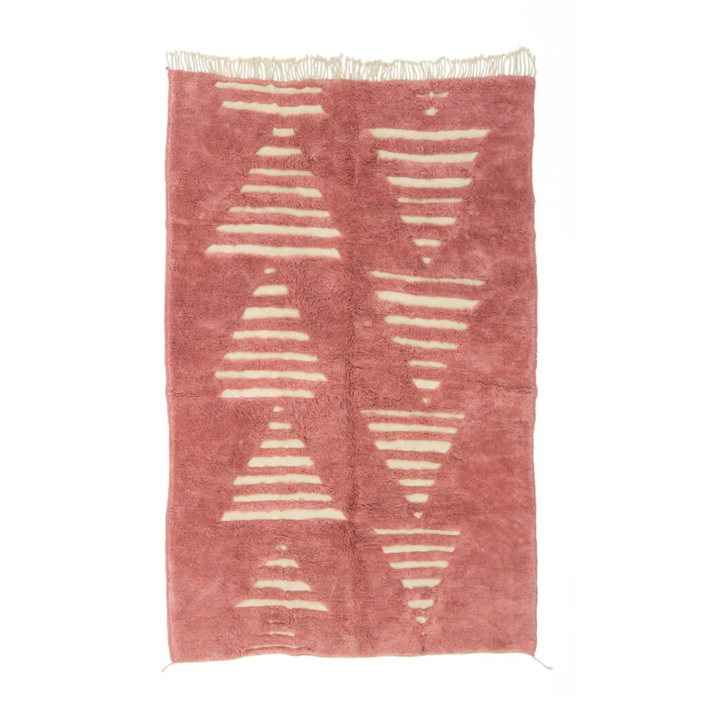 A rectangular pink textured rug with a series of beige triangular patterns and fringed edges, this hand-knotted Moroccan rug adds a touch of luxury to any space.