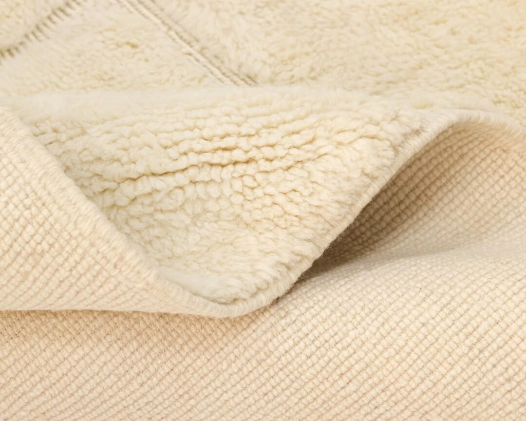 Close-up of a soft, cream-colored fleece textile, showcasing its texture and layered folds.