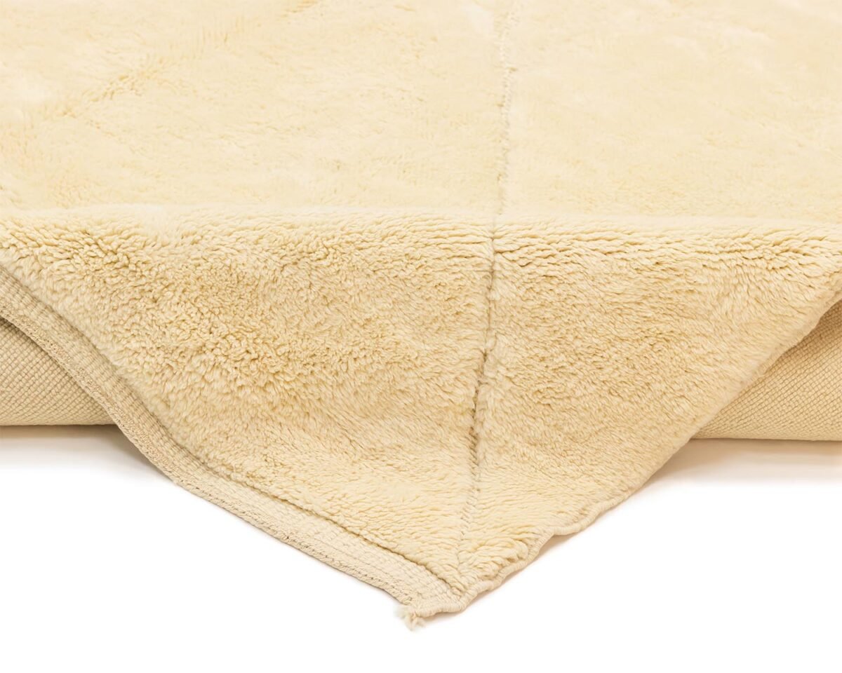 Close-up of a beige, fluffy throw with a folded corner, highlighting its soft texture and plush thickness.