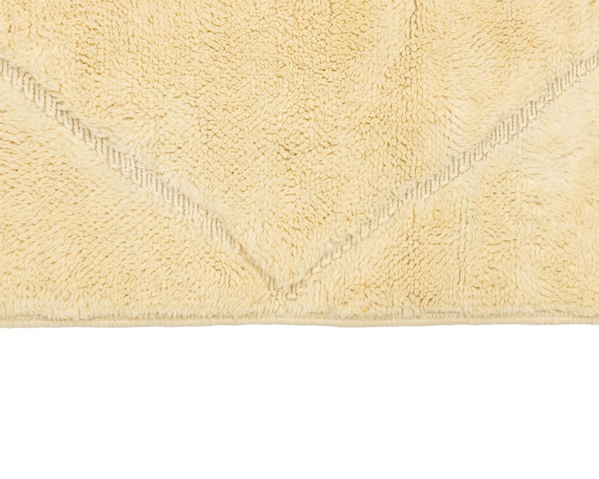 Close-up of a beige textured fabric featuring a triangular woven pattern along the edge. The intricate details and soft tones create an elegant touch, perfect for adding warmth to any room.