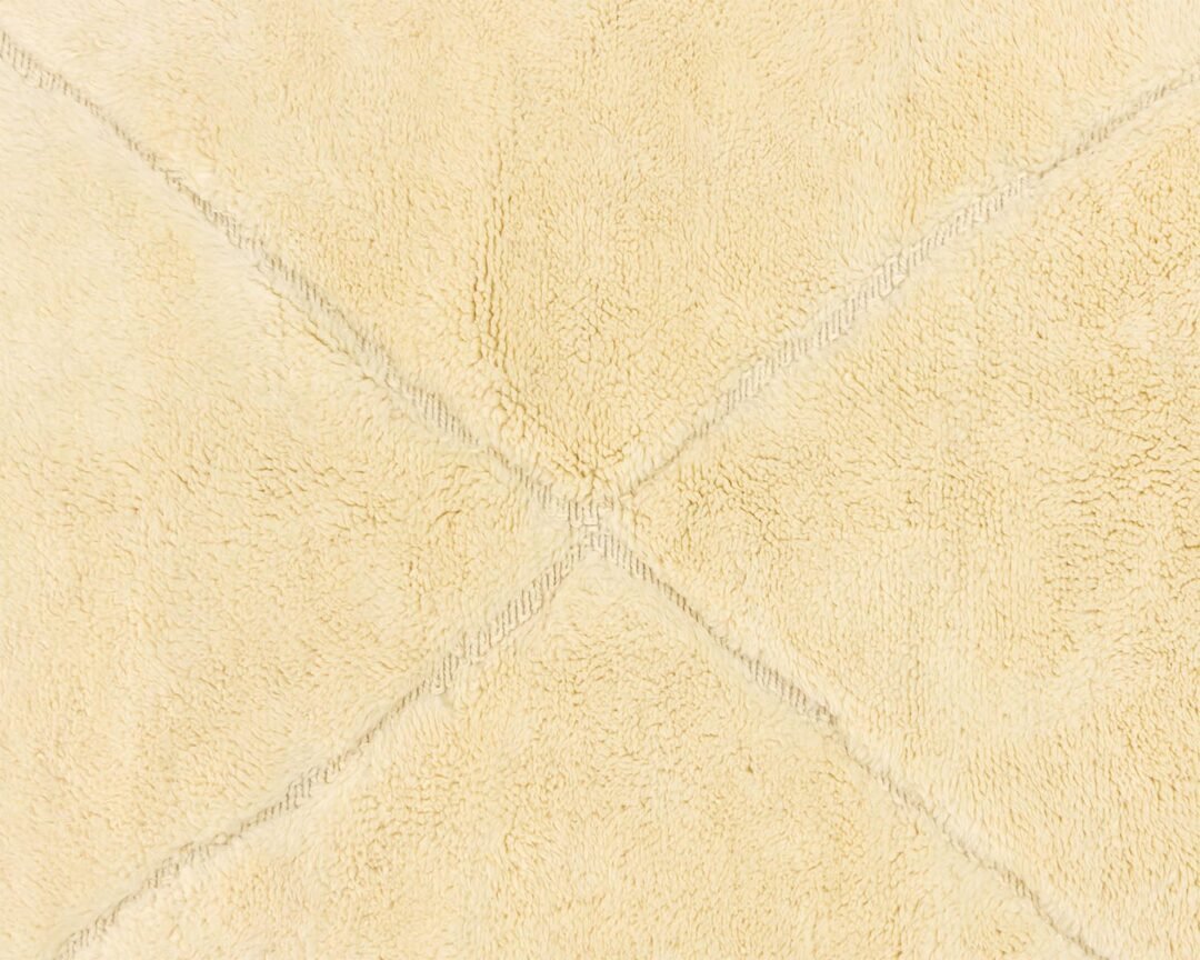 Close-up of a beige textured fabric featuring intersecting stitched lines that form an elegant X pattern.