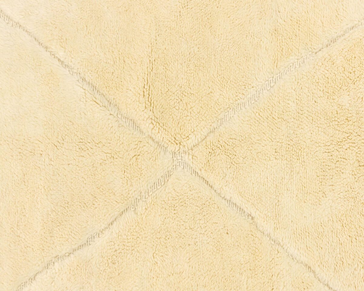 Close-up of a beige textured fabric featuring intersecting stitched lines that form an elegant X pattern.