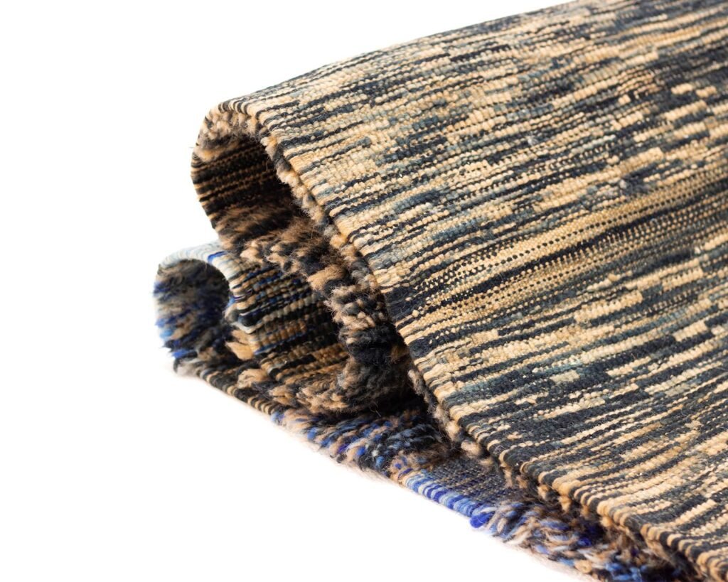 Folded textured rug with a blue, beige, and black pattern.