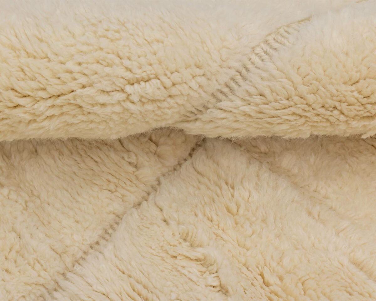 A close-up of beige, fluffy fabric showcases a textured, quilted pattern, evoking a sense of warmth and coziness.