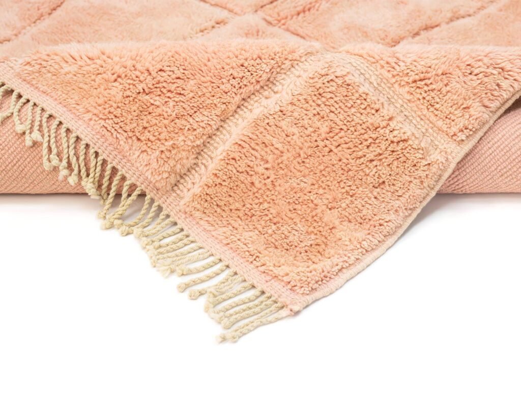 Close-up of a fluffy peach towel with fringed edges, adorned with a delicate pattern.